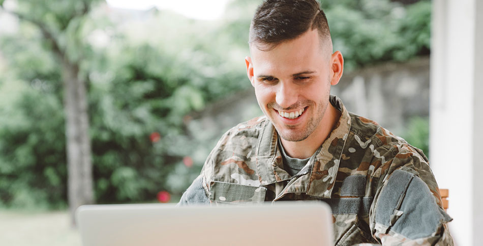 Man in military uniform working on computer.