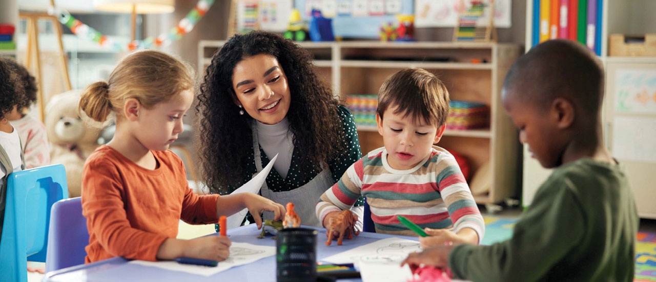 Teacher working with several small children at a table