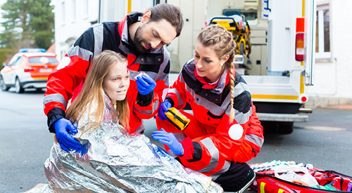 2 Emergency Medical Technicians aiding an injured girl