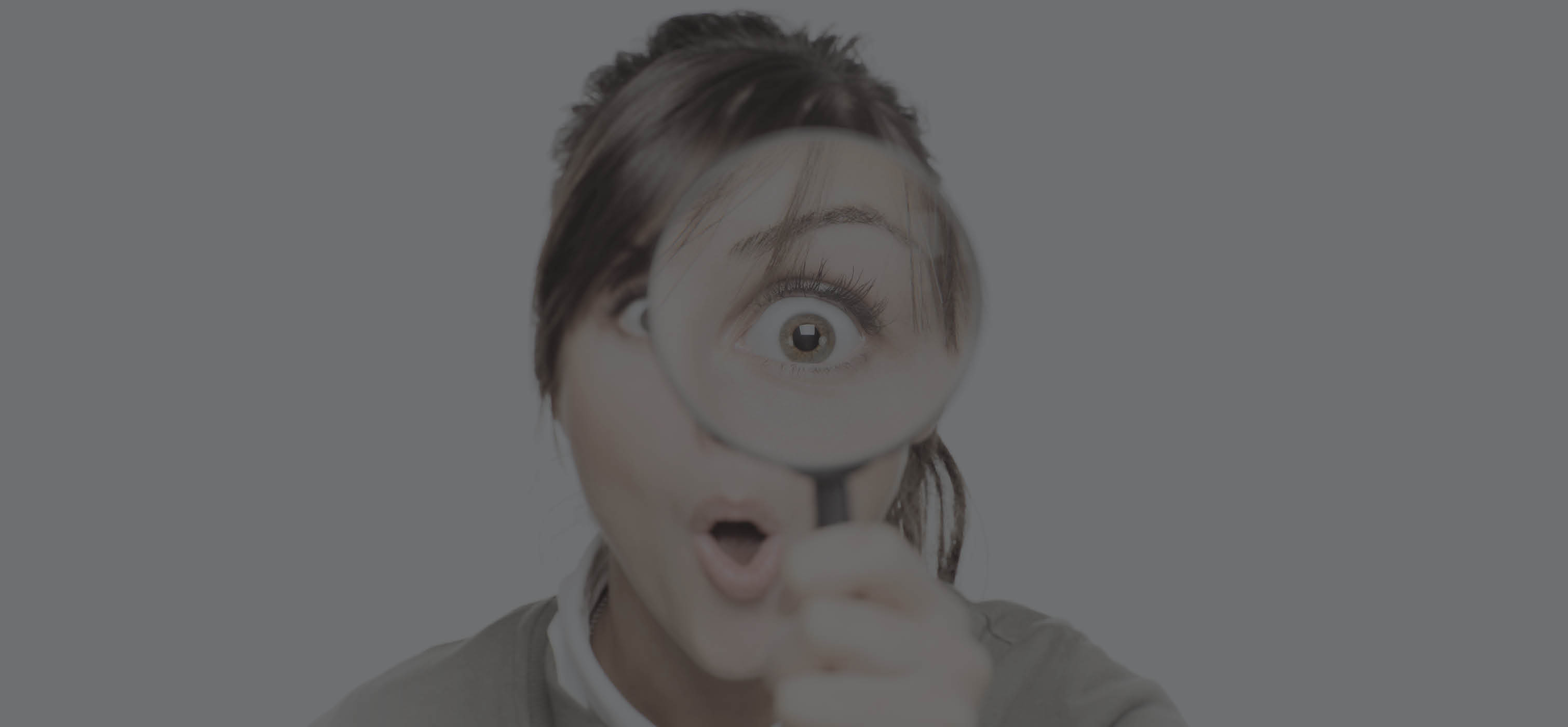 Person holding magnifying glass in front of them toward the camera making their left eye look large