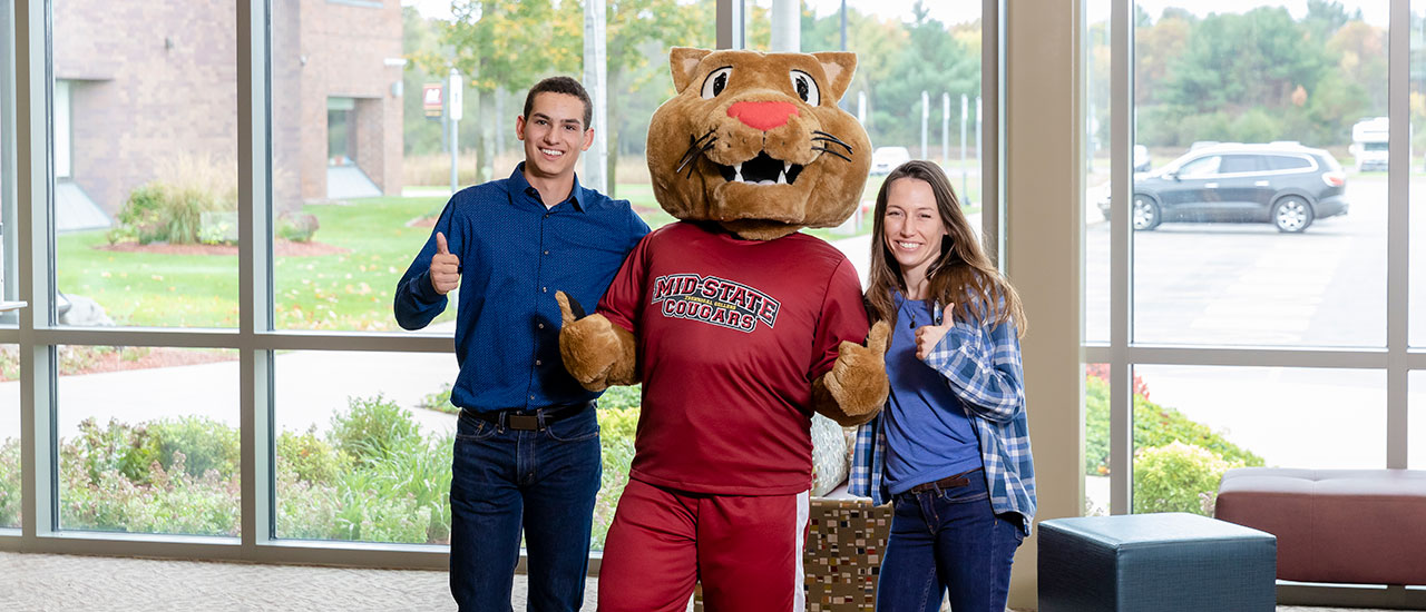 2 students standing with Mid-State mascot Grit