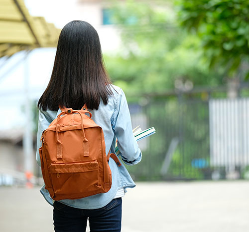 Student standing with a backpack on facing the other way.