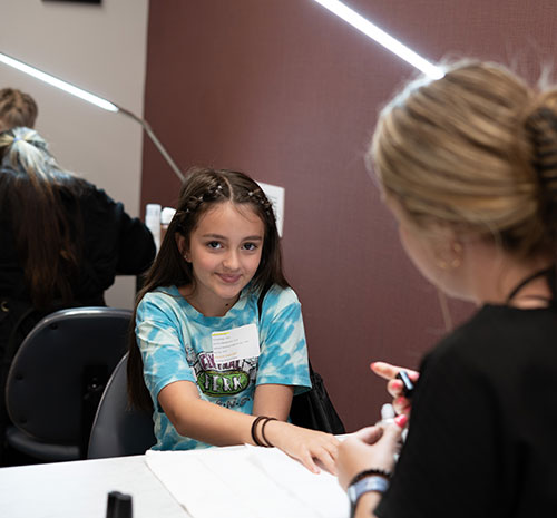 College Camp 2024 attendee gets her nails done in the cosmetology session.