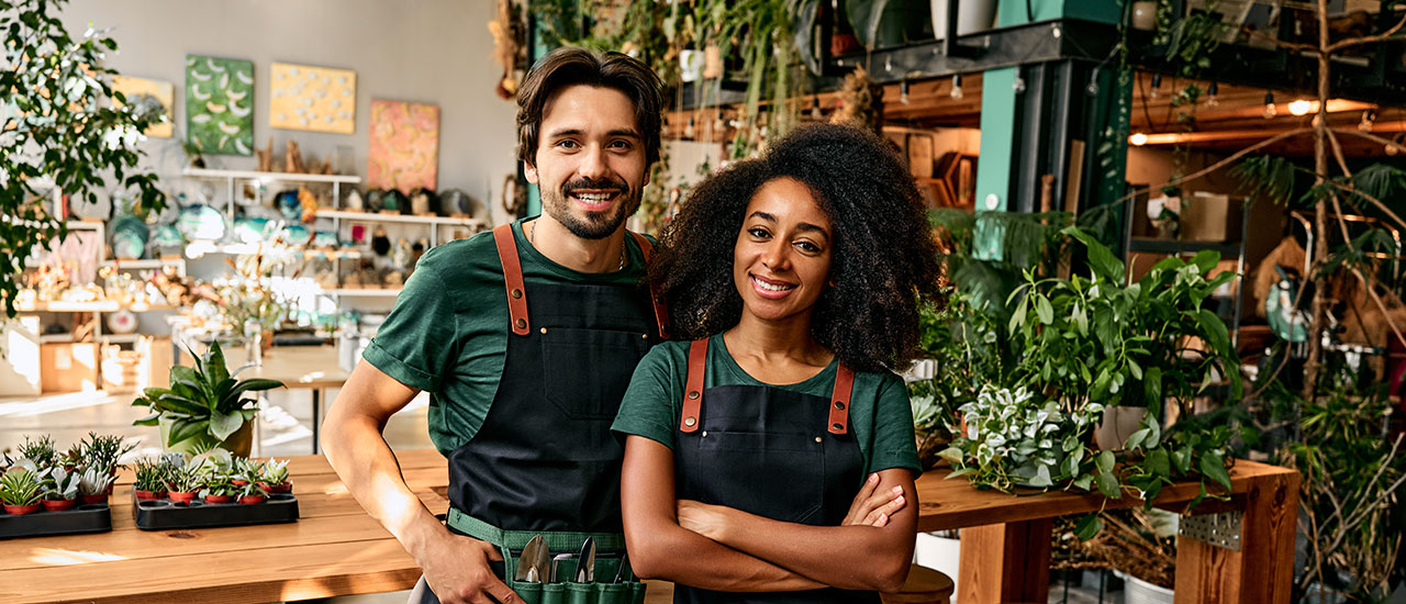 Two people standing in shop surrounded by plants