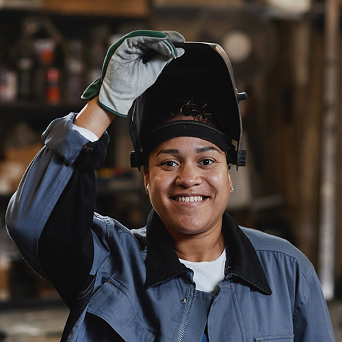 Woman welder lifting up welding helmet.