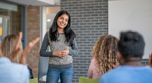 Person standing in front of a group of people sitting presenting information