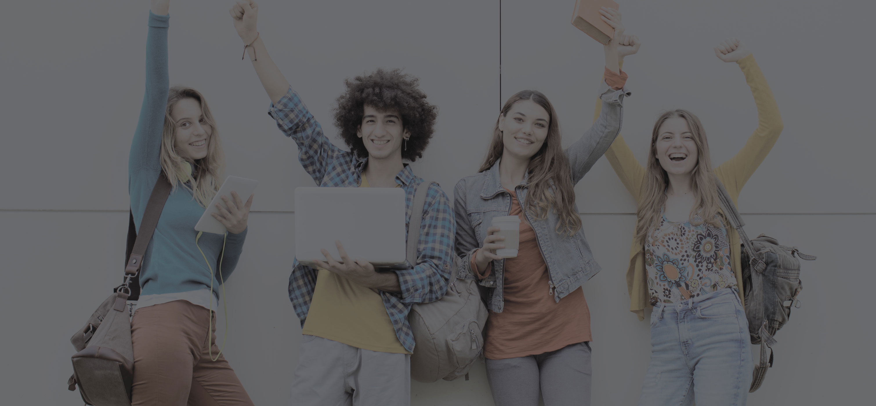 A group of four students standing together with backpacks, smiling and raising their arms in celebration.