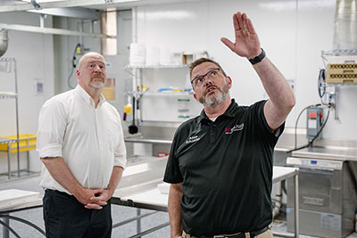DATCP Secretary Randy Romanski, left, looks on while Mid-State Meat Cutting and Butchery Instructor Adam Schlafke conducts a tour of the meat cutting lab at Auburndale High School.