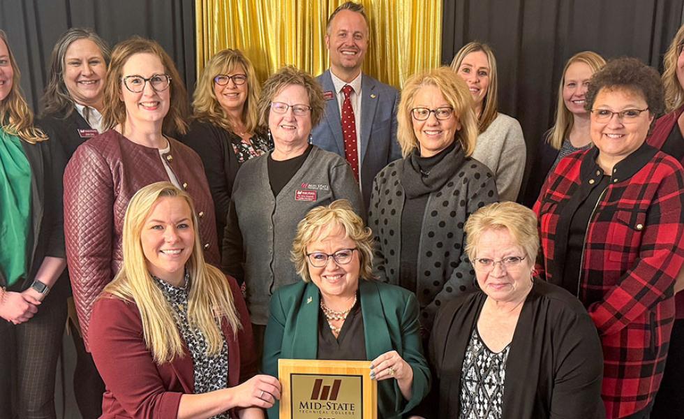 Mid-State Technical College was presented with the Marshfield Area Chamber of Commerce and Industry award at MACCI’s Annual Dinner on Wednesday, January 29, in Marshfield, Wis. Pictured, front row, are Dr. Alex Lendved, Mid-State dean of the Marshfield Campus and School of Applied Technology; Dr. Shelly Mondeik, Mid-State president; and Betty Bruski-Mallek, Mid-State Board of Directors member. They are surrounded by Mid-State staff. 