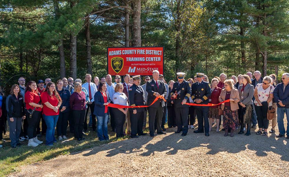 Mid-State Technical College staff and Adams County Fire District leadership look on while Rick Anderson, dean of Mid-State’s Adams Campus and School of Public Safety, helps Fire Chief Rodger Lauritzen of the Adams County Fire District cut the ribbon on the site of the Adams County Fire District Training Center in Adams, Oct. 8, 2025.