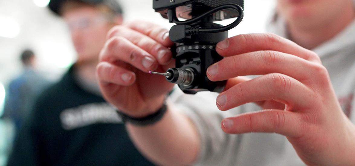 A student sets up a coordinate measuring machine (CMM) to gather data points from a machined part