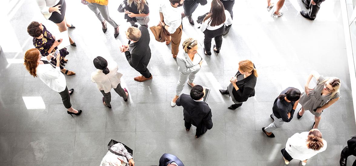 Birds eye view of people standing around together in a conference room.