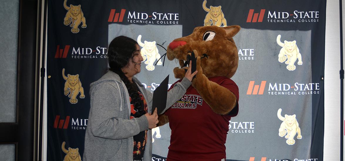 Akayla Reyes, a 16-year-old Boys & Girls Club member from Wisconsin Rapids, high-fives Mid-State Technical College’s mascot, Grit, after receiving her certificate of completion from the Cougar Paths: Exploring Futures Together program at the end-of-year celebration event on May 28 on the Wisconsin Rapids Campus.