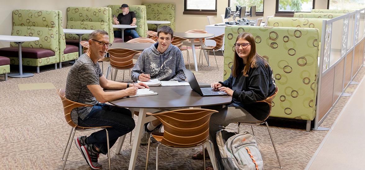 Mid-State Technical College students sit with their parent at a table in the common area on the Marshfield Campus.