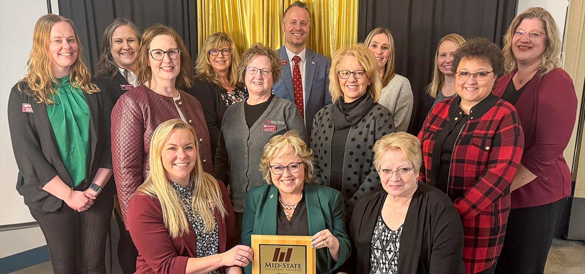 Mid-State Technical College was presented with the Marshfield Area Chamber of Commerce and Industry award at MACCI’s Annual Dinner on Wednesday, January 29, in Marshfield, Wis. Pictured, front row, are Dr. Alex Lendved, Mid-State dean of the Marshfield Campus and School of Applied Technology; Dr. Shelly Mondeik, Mid-State president; and Betty Bruski-Mallek, Mid-State Board of Directors member. They are surrounded by Mid-State staff. 