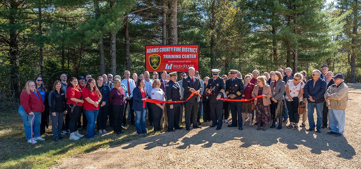 Mid-State Technical College staff and Adams County Fire District leadership look on while Rick Anderson, dean of Mid-State’s Adams Campus and School of Public Safety, helps Fire Chief Rodger Lauritzen of the Adams County Fire District cut the ribbon on the site of the Adams County Fire District Training Center in Adams, Oct. 8, 2025.